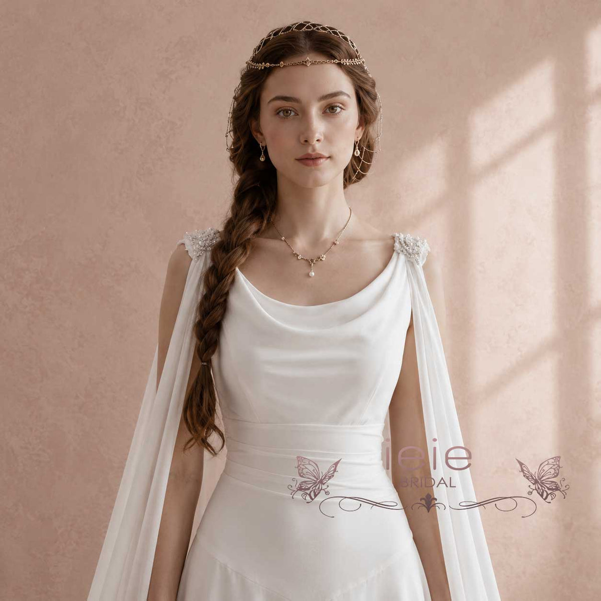 A woman wearing a white bridal gown with draped sheer fabric over the shoulders and a delicate headpiece, posed against a soft beige textured wall with warm window light casting shadows.
