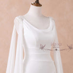 White bridal gown on a mannequin with draped sheer sleeves and embellished shoulder details, shown against a soft beige background. The brand name 'ieie BRIDAL' is watermarked on the front.